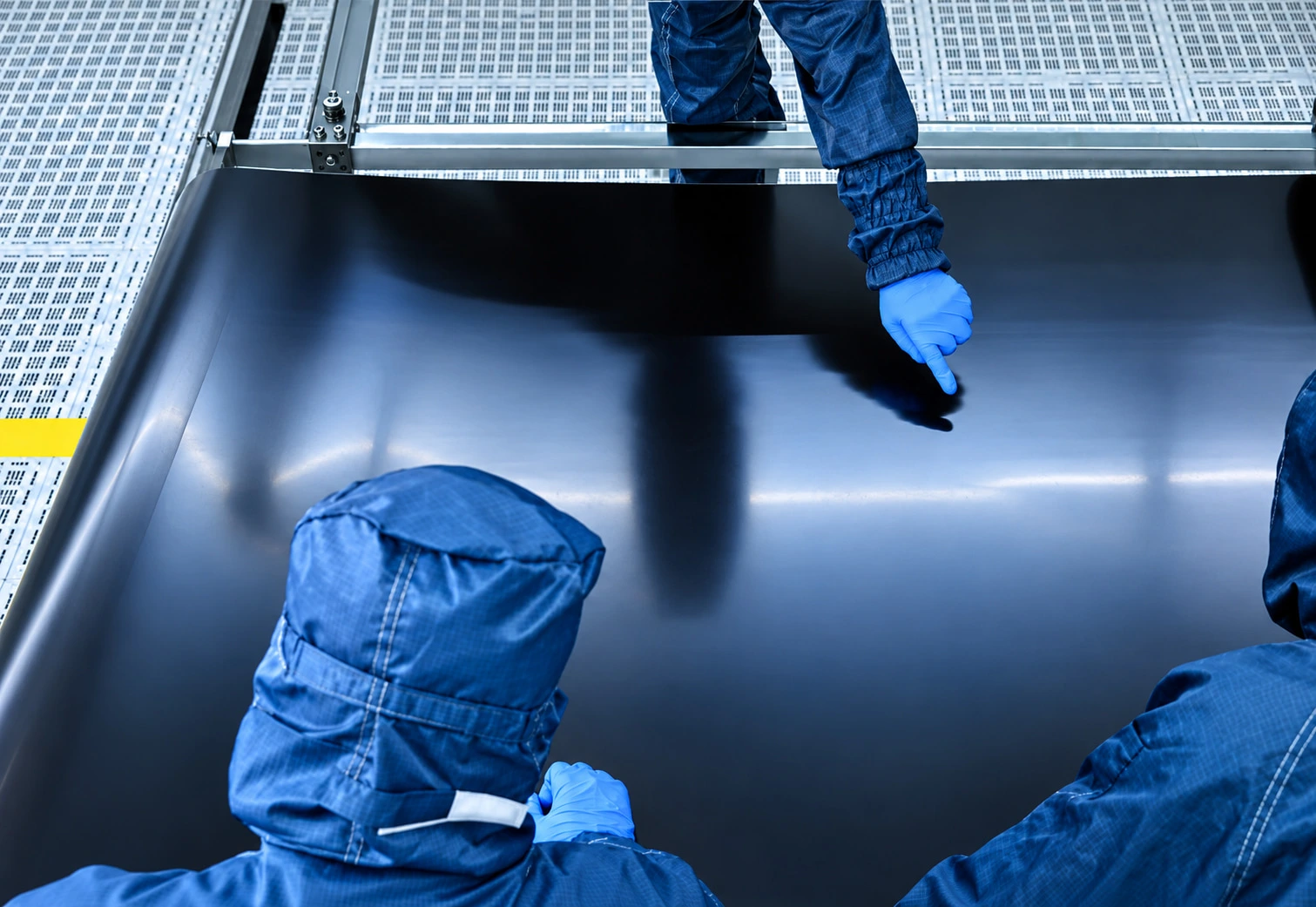 Technicians handling a large electrochromic film on a roll-to-roll line